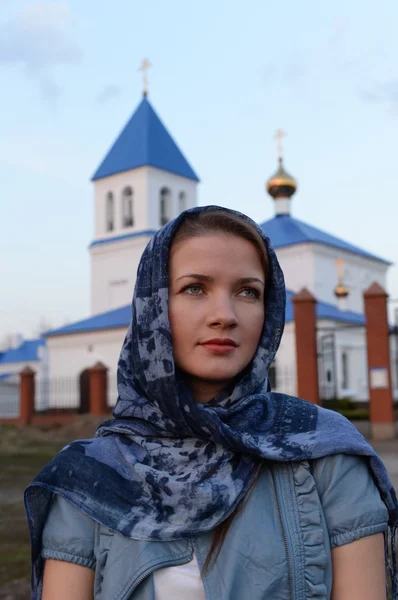 A girl of Slavic Russian appearance in a scarf on the background of the church Royalty Free Stock Images