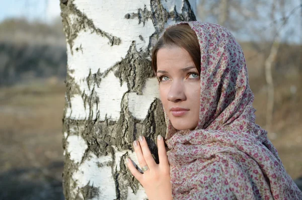 Menina russa em um lenço em uma floresta de vidoeiro perto — Fotografia de Stock