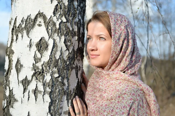 Menina russa em um lenço em uma floresta de vidoeiro perto — Fotografia de Stock