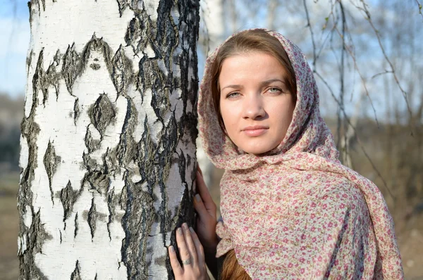 Menina russa em um lenço em uma floresta de vidoeiro perto — Fotografia de Stock