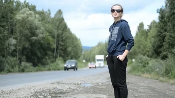 Giovane ragazza cercando di fermare la macchina sulla strada — Video Stock