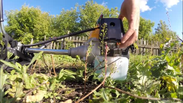 Man gets petrol scythe at the farmers plot — Stock Video