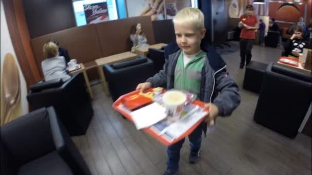 Een kleine jongen in een restaurant in Mc'Donalds — Stockvideo