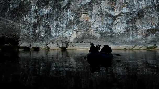 Silhouettes of tourists in a boat on the water against the backdrop of beautiful cliffs — Stock Video