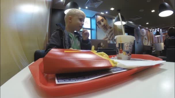 Een kleine jongen in een restaurant in Mc'Donalds — Stockvideo