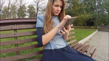 Tablet bilgisayar sonbahar parkta okuma kız