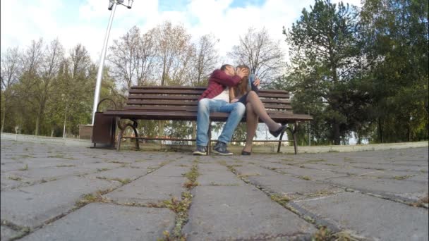 Homem e mulher no parque de outono em um banco — Vídeo de Stock