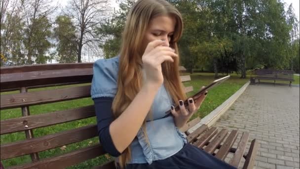 Menina leitura tablet computador no parque de outono — Vídeo de Stock