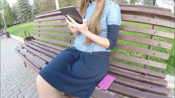 Menina leitura tablet computador no parque de outono — Vídeo de Stock