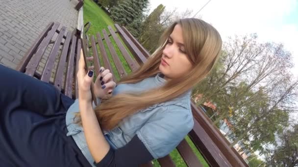 Chica leyendo tableta ordenador en el parque de otoño — Vídeos de Stock