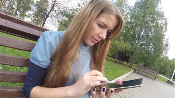 Menina leitura tablet computador no parque de outono — Vídeo de Stock