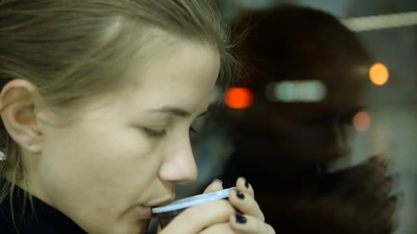 Ville, vitrine en verre. Femme déprimée buvant du thé près de la fenêtre à la maison — Video