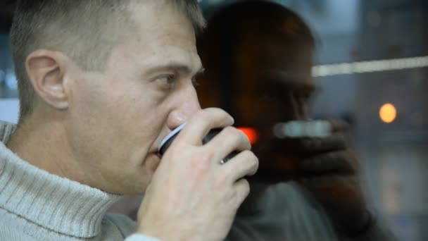 Ville, vitrine en verre. Homme déprimé buvant du thé près de la fenêtre à la maison — Video