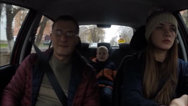 Family of three people traveling around the city in a car. Mother, father, son — Stock Video