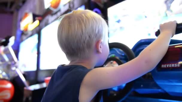 Un niño jugando una máquina tragaperras en un parque de diversiones — Vídeos de Stock