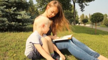 Genç anne oğluyla parkta bir yürüyüş ile ilgili bir kitap okuma
