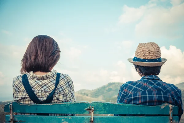 Face arrière d'un beau couple assis sur une chaise en bois avec vue sur le ciel — Photo