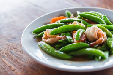 Karides heyecan ve seçici odak ile beyaz plaka üzerinde kızarmış ve yeşil bezelye