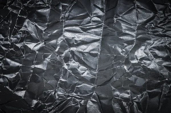 Background of crumpled black paper with selective focus and under exposure