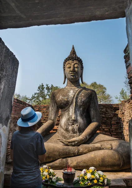 Señora rezar sentado estatua de Buda en el templo antiguo Tailandia — Foto de Stock