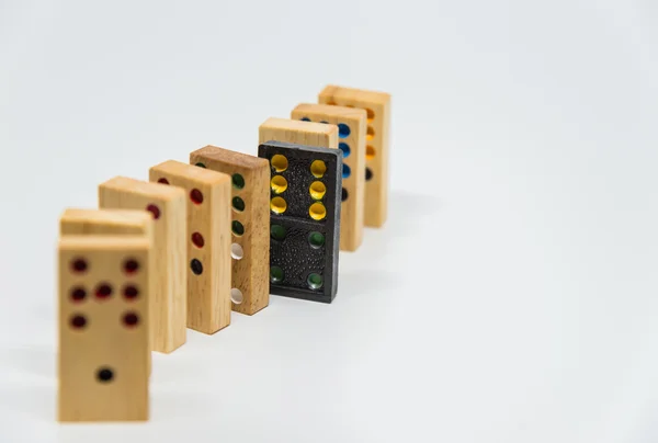 Secuencia de dominó de madera con dominó de plástico negro sobre fondo blanco con enfoque selectivo —  Fotos de Stock