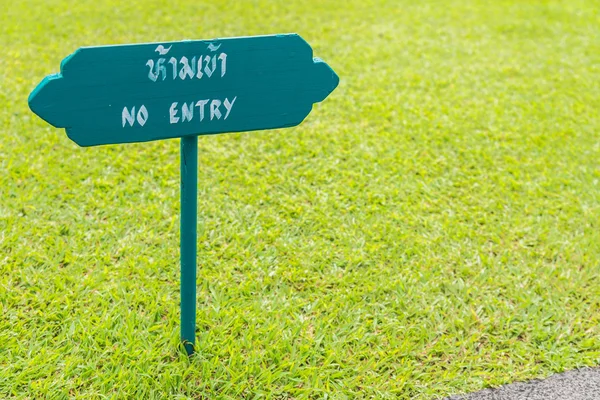 Wooden sign NO ENTRY in green grass garden