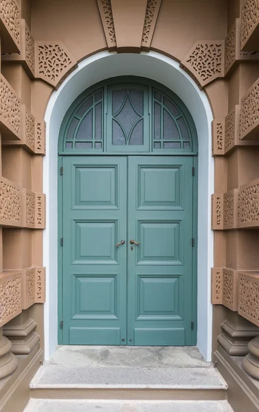 Porte fermée en bois vert de style européen avec bâtiment brun — Photo