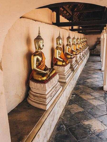 Row of golden peaceful sitting buddha statue in the Thailand temple