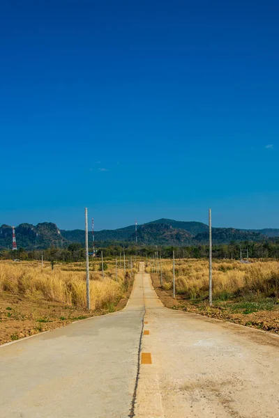 真っ青な空で乾燥した牧草地の草が両側に乾燥した田舎道で熱い温度旅行の概念のアイデア — ストック写真