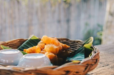 Bol yağda kızartılmış hamur, muz yaprağının üzerinde bambu sepeti ve ahşap tahtada kahvaltı yemeği için sabah yumuşak güneş ışığıyla birlikte sabahleyin