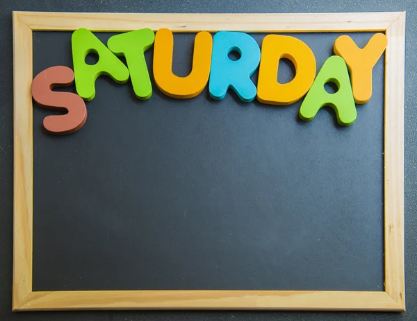 Colorful wooden word Saturday on black board — Stock Photo, Image