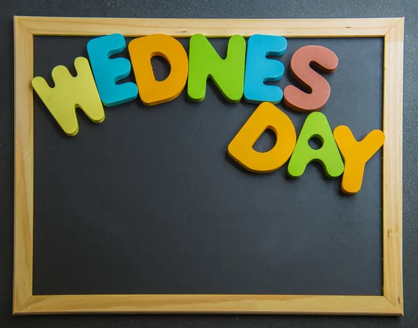 Colorful wooden word Wednesday on black board — Stock Photo, Image
