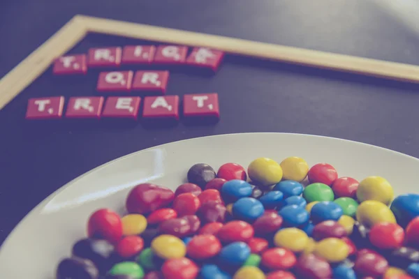 Trick or Treat mot sur le tableau noir avec des bonbons au chocolat coloré7 — Photo
