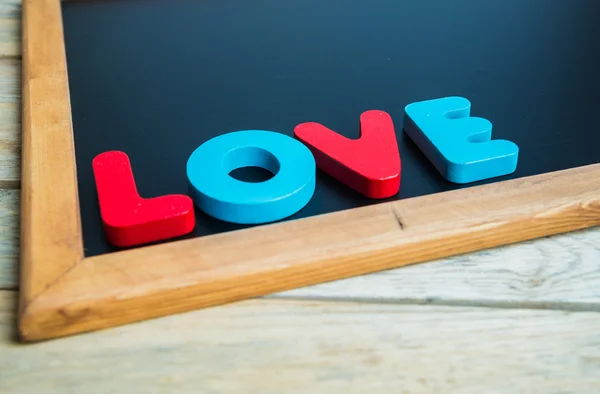 Palabra de madera AMOR en la esquina de la pizarra negra 1 —  Fotos de Stock