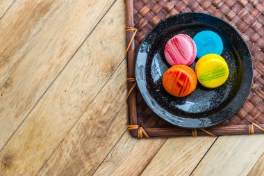 Ahşap zemin 7 üzerinde siyah tabak içinde renkli macaron