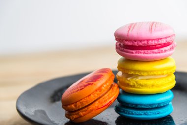 Ahşap zemin 2 üzerinde siyah tabak içinde renkli macaron