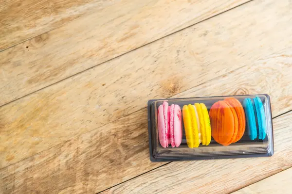 Kolorowy macaron w plastikowe pudełko na drewnianej podłodze 4 — Zdjęcie stockowe