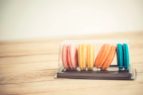 Kolorowy macaron w plastikowe pudełko na drewnianej podłodze w Vintage tematu — Zdjęcie stockowe