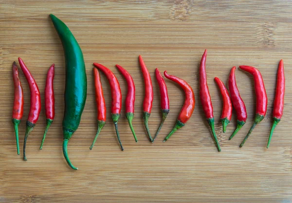 Eine große grüne Chilischote in kleiner roter Chilischote beim Schneiden — Stockfoto