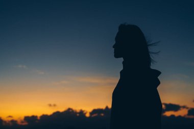 Dışarıda, dramatik bir günbatımı gökyüzüne karşı duran bir kadının silueti. Yansıma, özgürlük, yalnızlık, farkındalık, duygusal güç ve kopyalama alanı ile gelecek düşünme kavramı