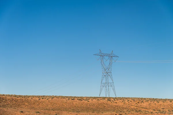Poste de alta tensão no deserto com o céu azul — Fotografia de Stock