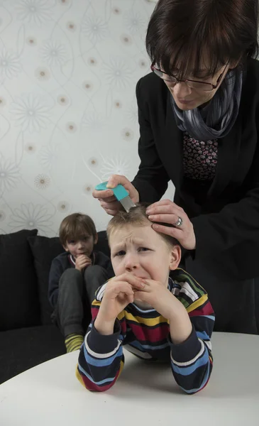 Mother looking for lice on youngsters head — Stock Photo, Image