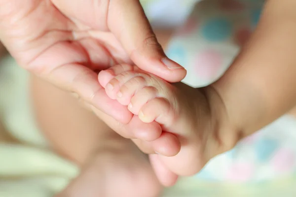 Mano che tiene un piede del bambino Foto Stock