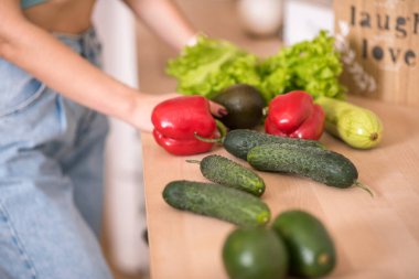 Genç bir kadın mutfakta taze sebze tutuyor..