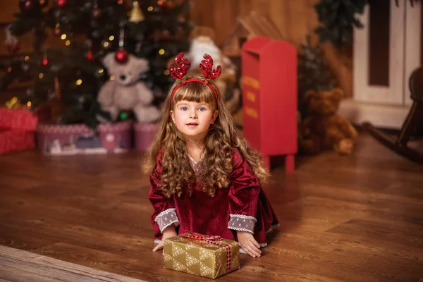 크리스마스 근처에 곱슬머리의 아름다운 아름다운 아이가 상자를 — 스톡 사진
