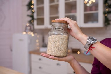 Mutfakta bir kavanoz kinoa tutan kadın.