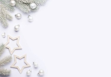 Yeni yıl teması üzerine hafif bir kompozisyon. Beyaz arka planda beyaz noel baloları olan ladin dalları.