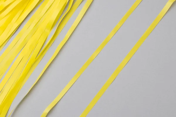 Fond gris abstrait avec des bandes de papier ondulé jaune vif. Photo De Stock