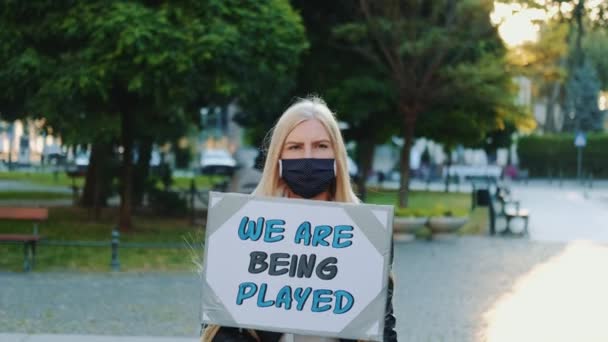 Pretty girl wearing medical mask protesting against authorities that playing human lives — Stock Video