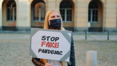 Sahte salgını protesto eden koruyucu maskeli genç bir kadın.